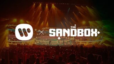 picture of the Sandbox metaverse logo and Warner Music logos side by side superimposed over a convert crowd